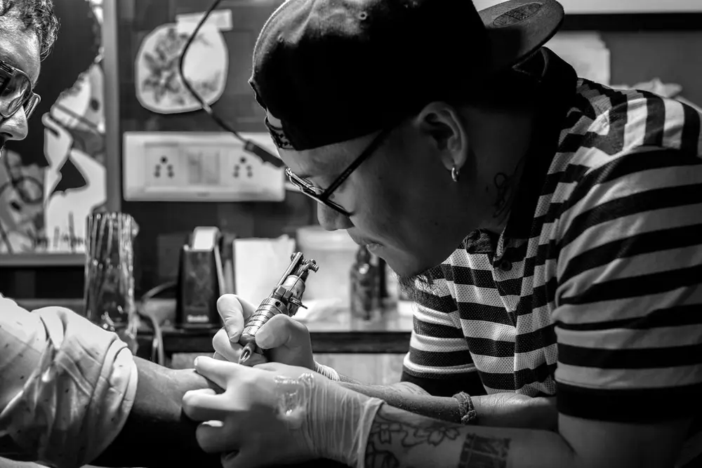 Mano de un tatuador profesional trabajando con máquina de tatuaje sobre la piel, referencia al oficio del tatuaje en Instagram Perú