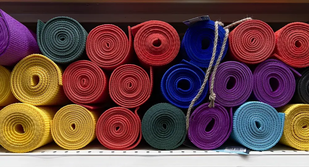 Esterillas de yoga enrolladas de distintos colores en un estante, referencia al contenido de yoga y bienestar en Instagram Perú