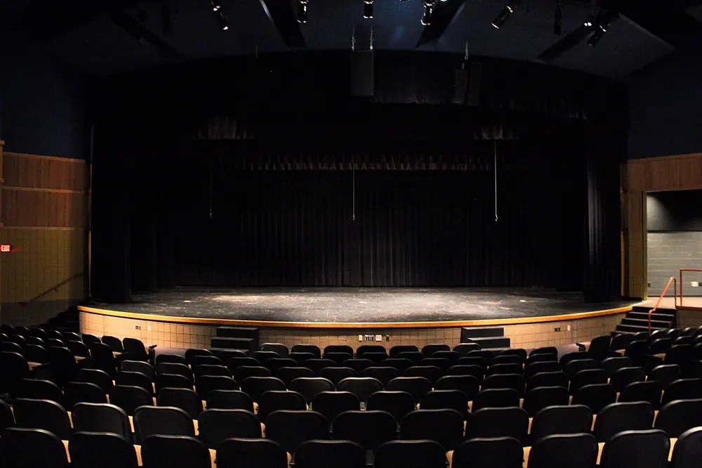 Escenario de teatro con telón oscuro y butacas vacías, referencia al contenido de artes escénicas en Instagram Perú
