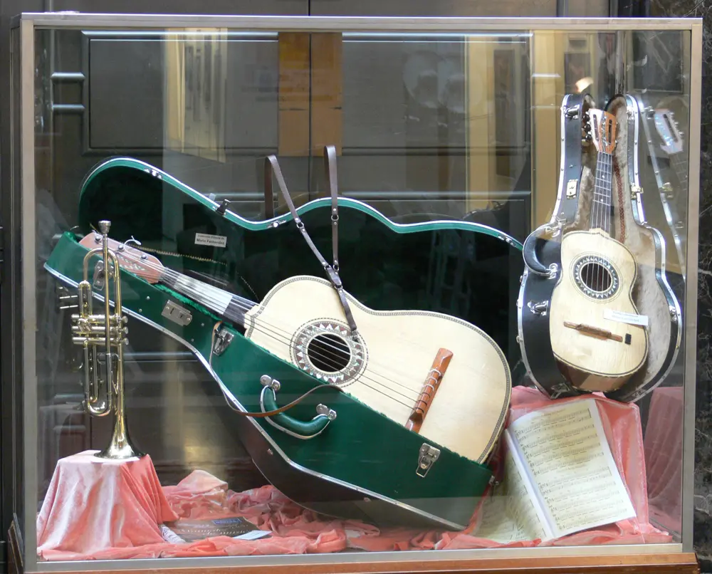 Guitarra, vihuela, trompeta y partituras de mariachi en una vitrina, referencia al contenido musical de una creadora peruana en Instagram