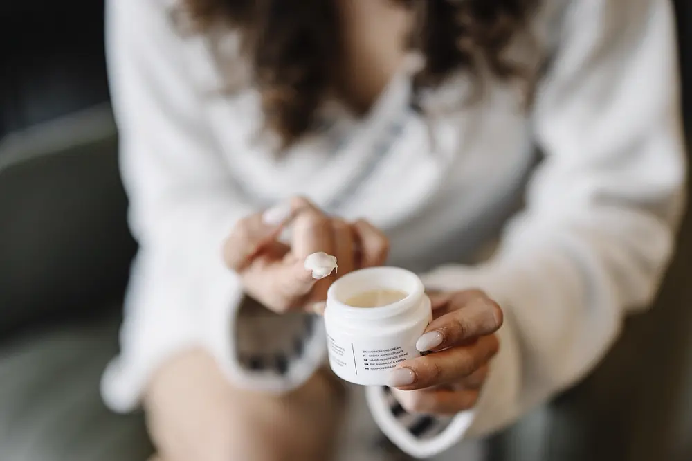 Manos aplicando crema hidratante de un frasco, referencia al contenido de skincare y selfcare en Instagram Perú