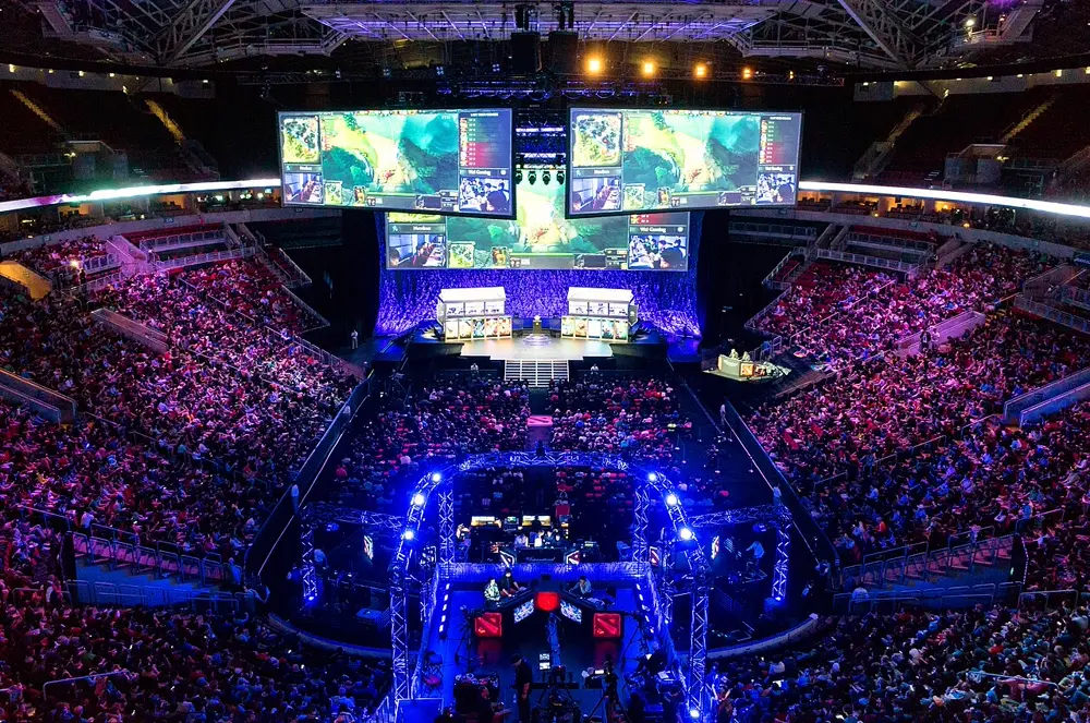 Arena llena durante un torneo de Dota 2 con pantallas gigantes y el escenario de los equipos, referencia al contenido de esports de @mespol en Instagram Perú