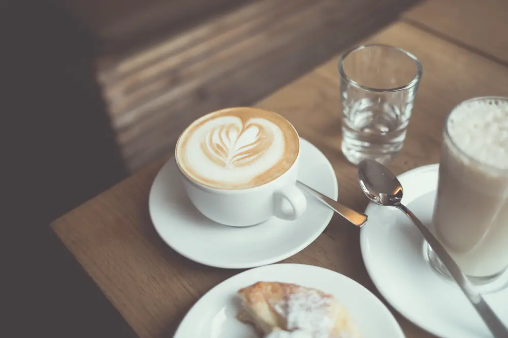 Café con arte latte sobre una mesa de madera en una cafetería, referencia al contenido lifestyle y de recomendaciones de cafeterías en Instagram Perú