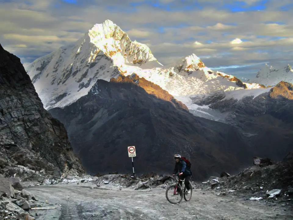 Ciclista de montaña en la carretera de Punta Olímpica frente al nevado Chopicalqui, referencia al contenido de MTB y alta montaña en Instagram Perú