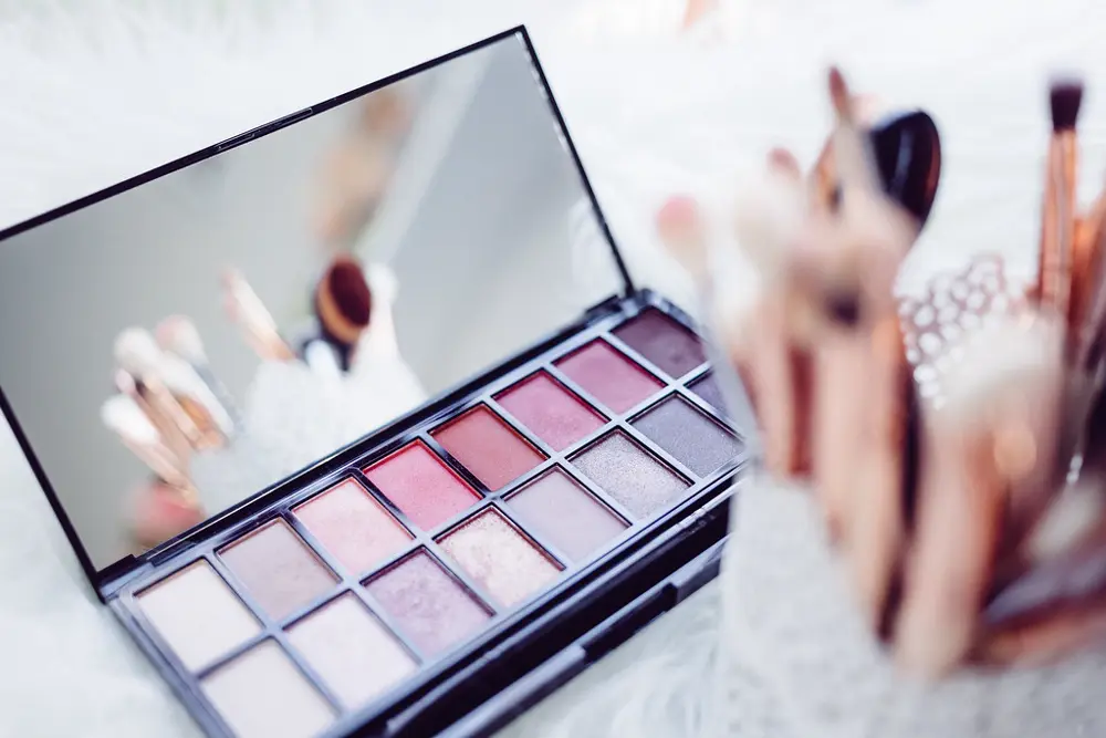 Paleta de sombras rosadas y brochas de maquillaje sobre una superficie blanca, referencia al contenido de belleza en Instagram Perú