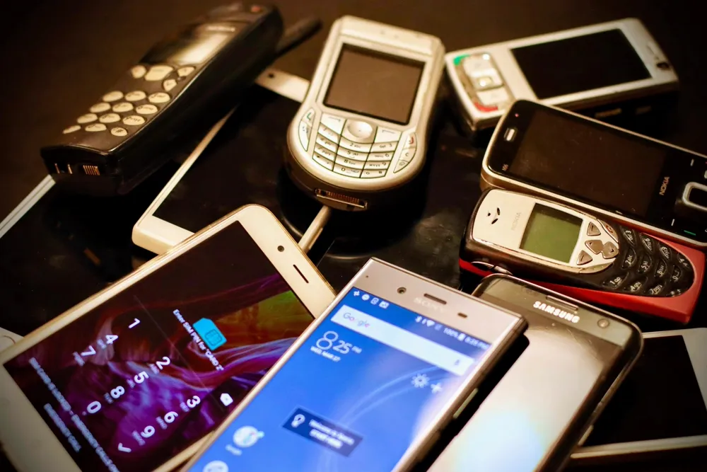 Varios teléfonos celulares apilados, representando una granja de bots política, en contraste con comprar seguidores para una sola cuenta